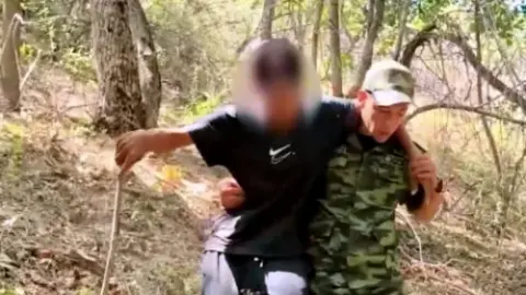Emergency rescuer helps a person descend a wooded slope