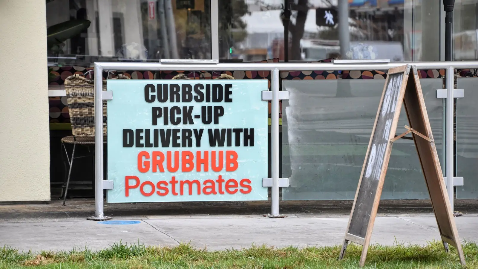 A restaurant sign advertising order pickup through Grubhub and Postmates