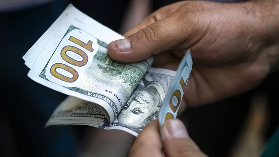 Hands counting modern US $100 banknotes