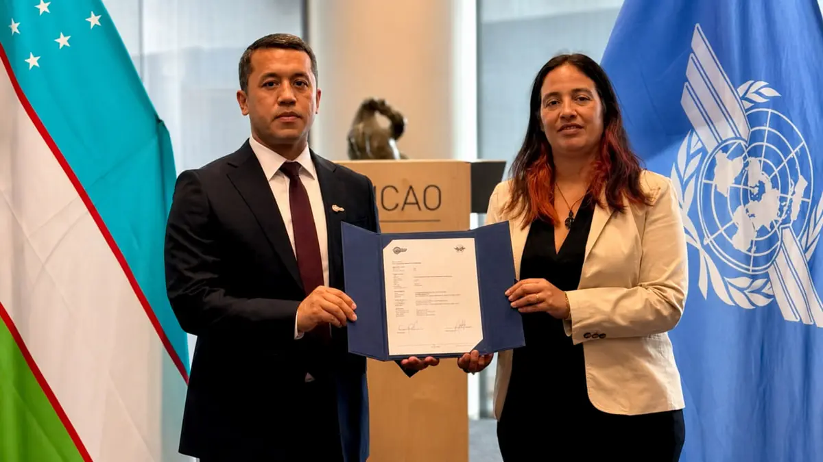 Uzbekistan and ICAO representatives holding a document on the biometric passport security update